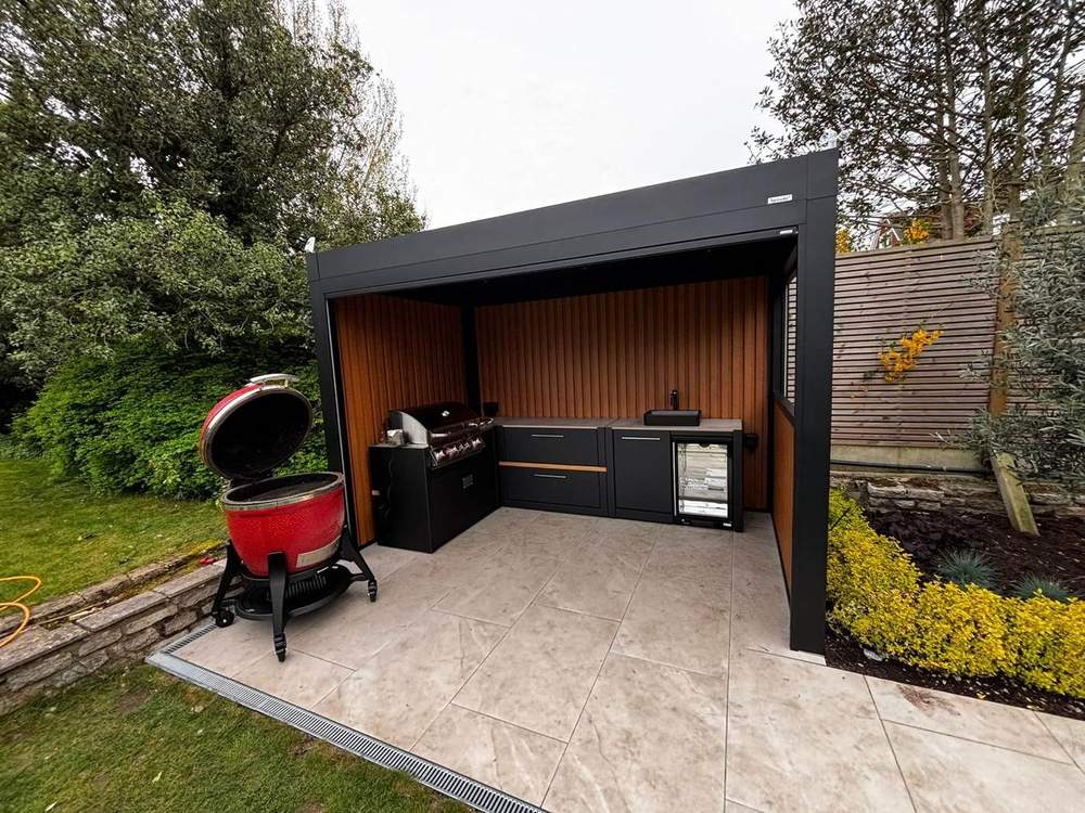 Outdoor kitchen sheltered by a black aluminium pergola