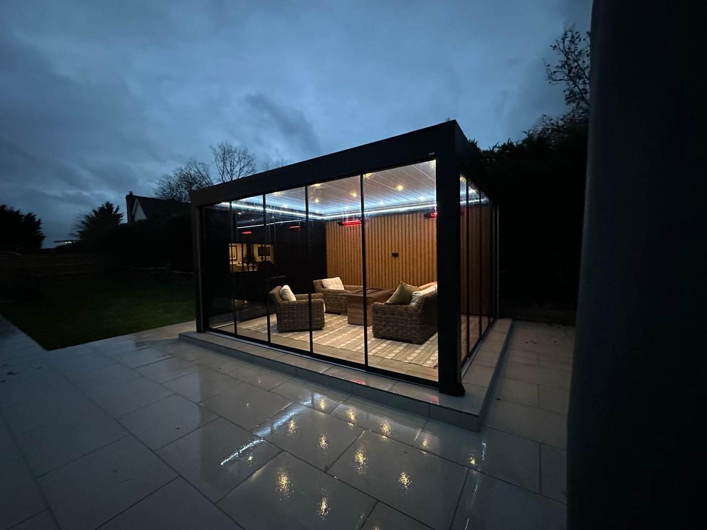Glass sided aluminium garden room lit at dusk