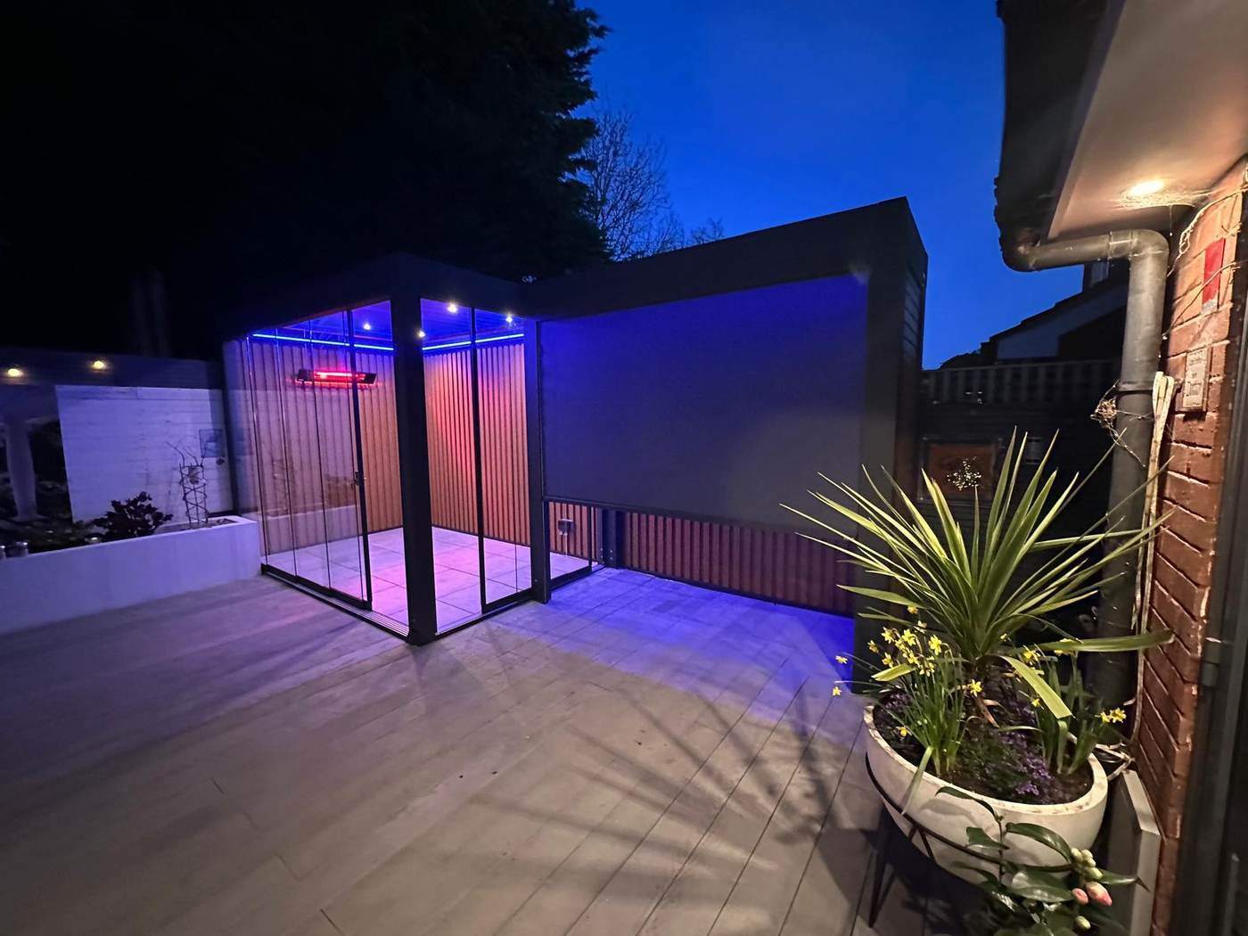 Aluminium pergola with side screens lowered and LED lighting at night